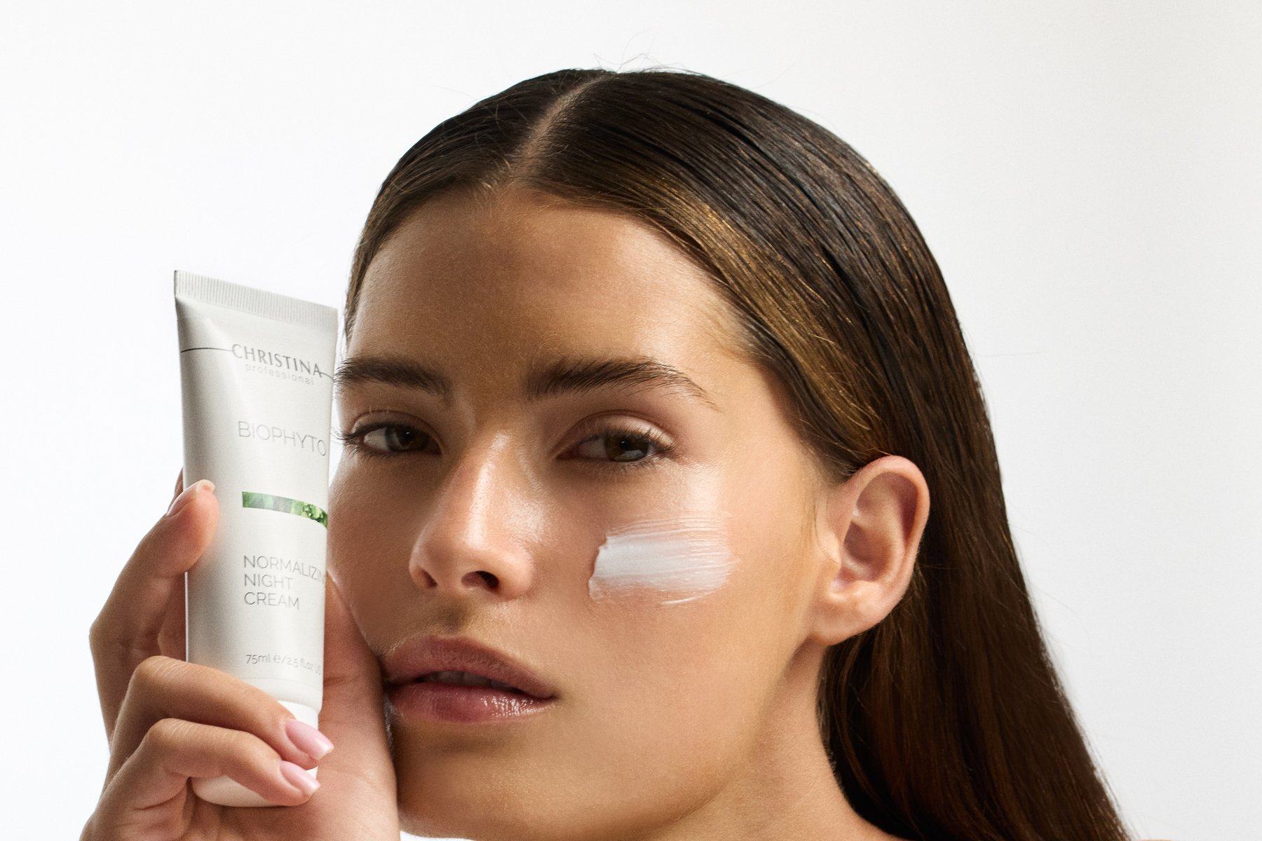 Nahaufnahme: aufgetragene Bio-Phyto-Creme auf der Wange, das Gebinde daneben
